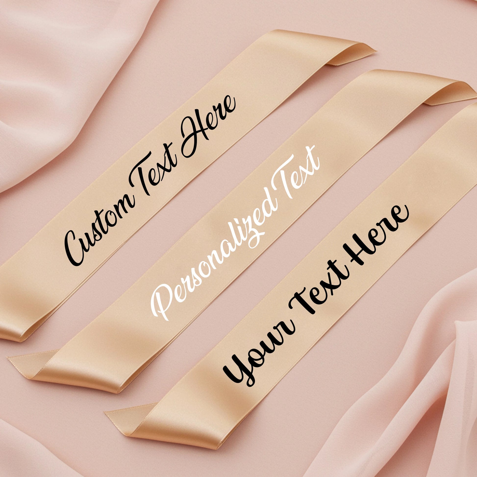 Three gold ribbons with customizable text on a pink fabric background