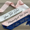 Three ribbons with customizable text on a wooden surface